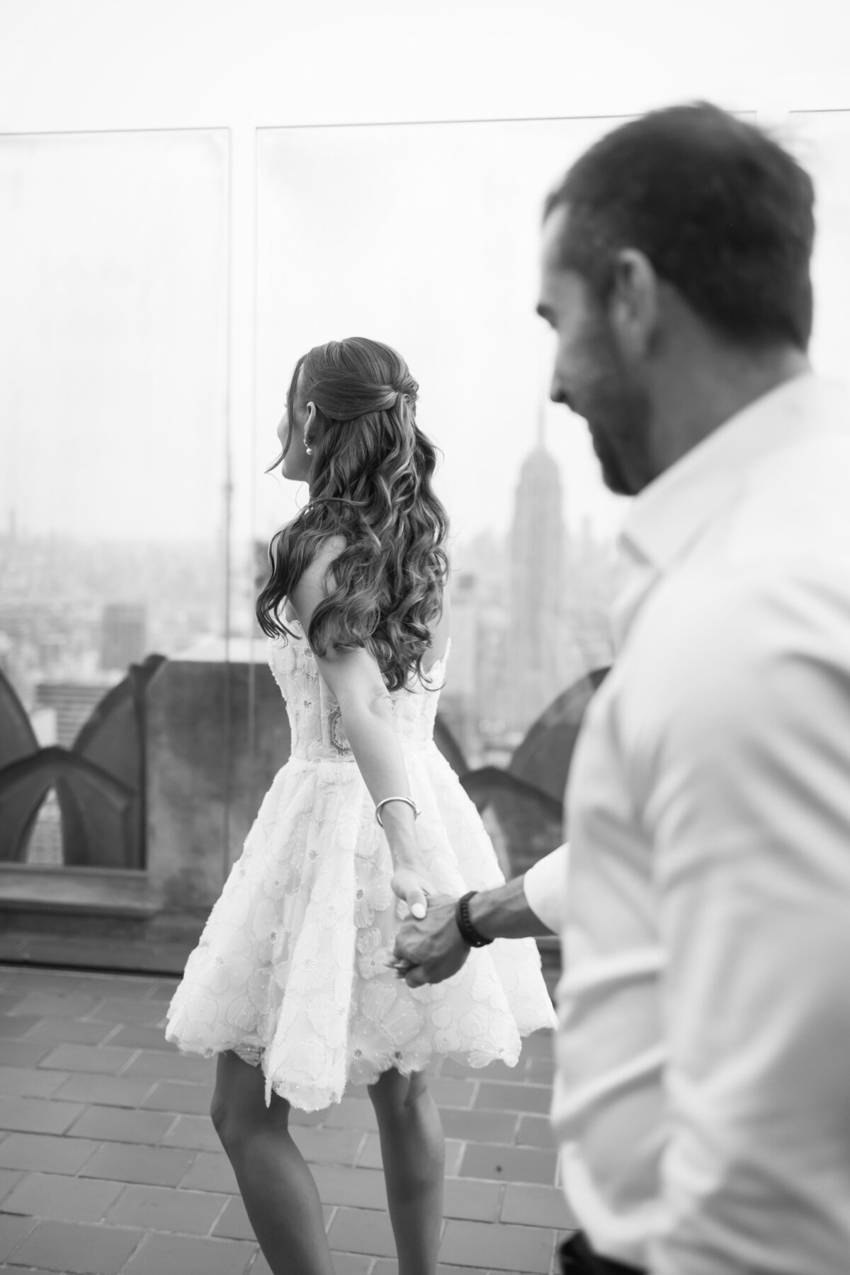 A bride and groom laugh together during their wedding shoot at Top of the Rock, with the city’s skyline providing an unforgettable scene.