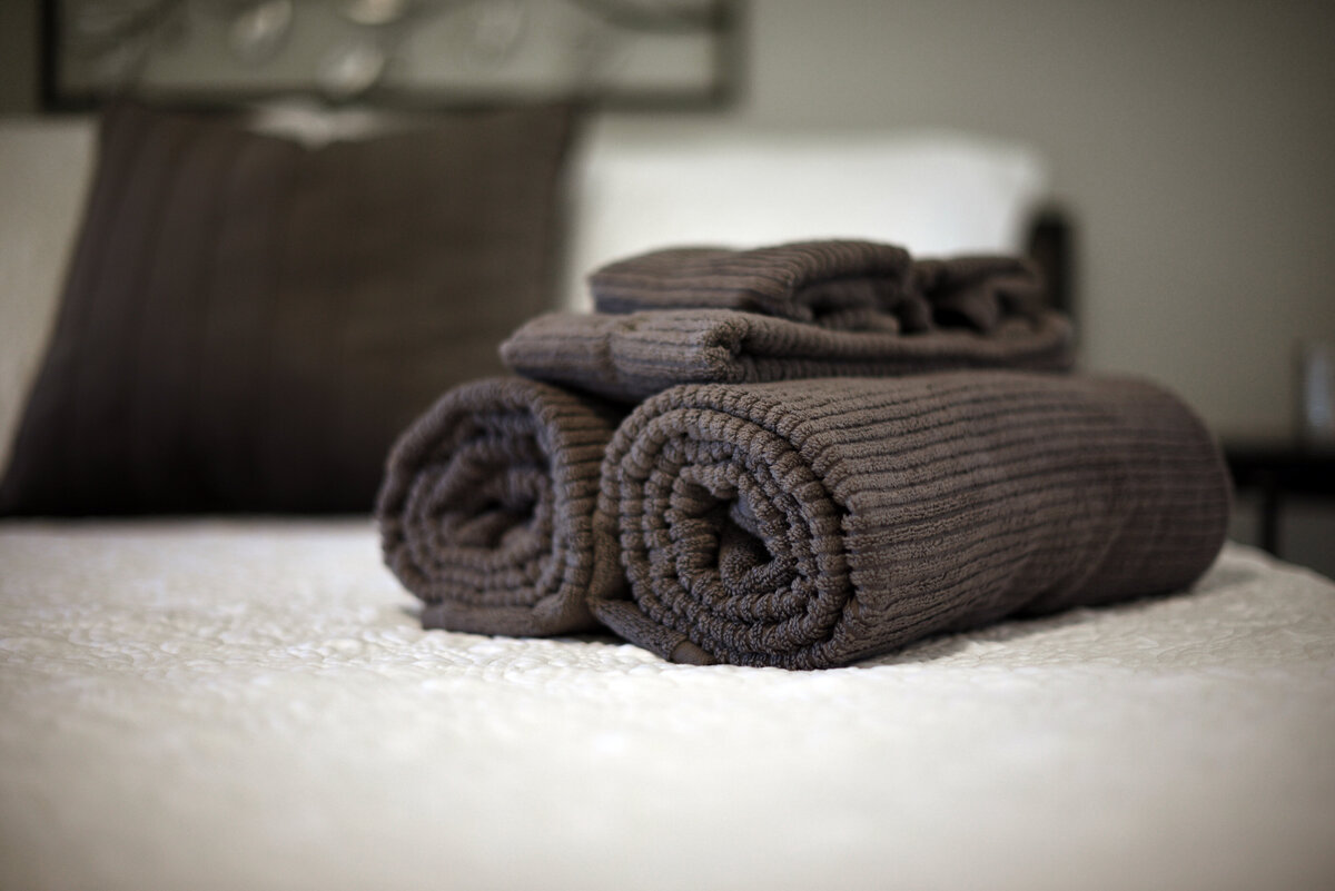 Close up of professionally staged rolled towels on bed