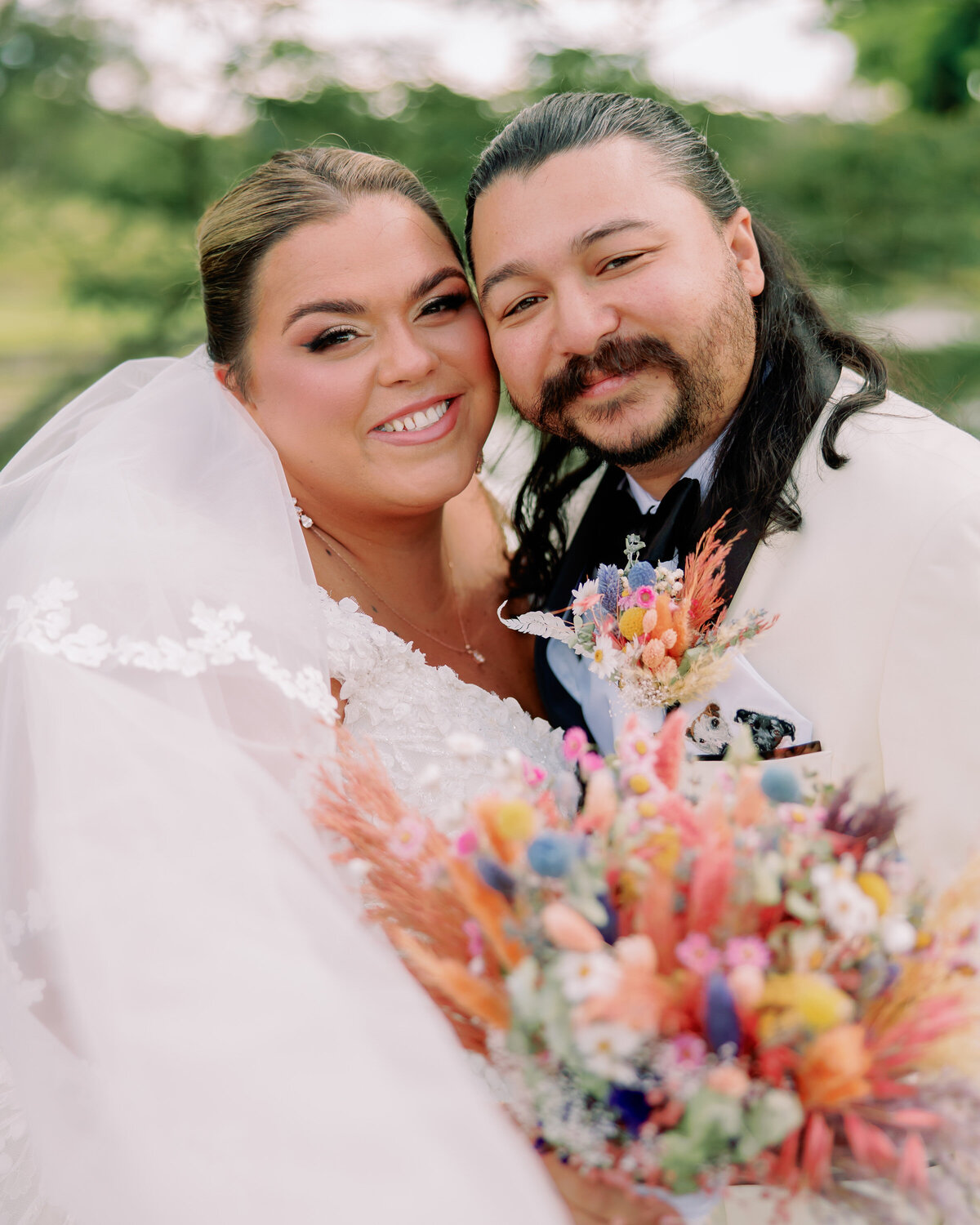 A newlywed couple standing cheek to cheek as they smile 