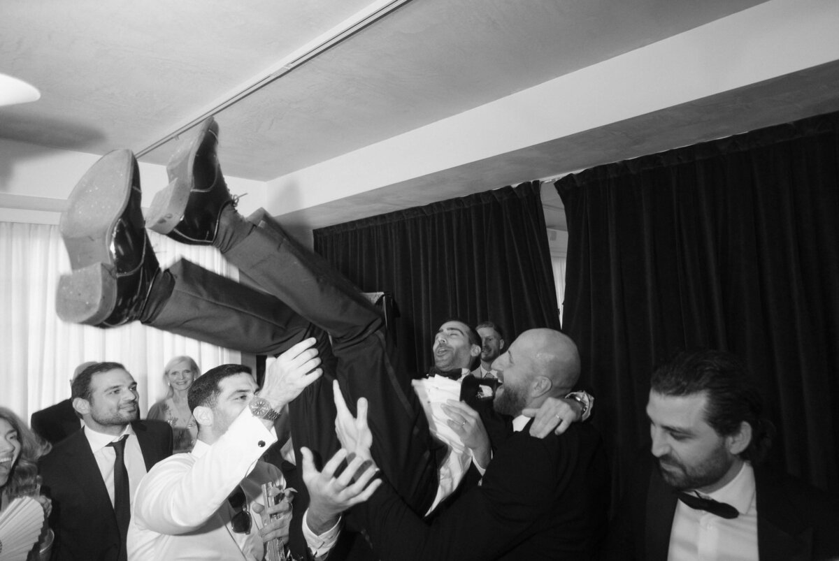 Groomsmen lifting groom in celebration on the dance floor

