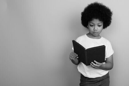 black and white image of kid holding book