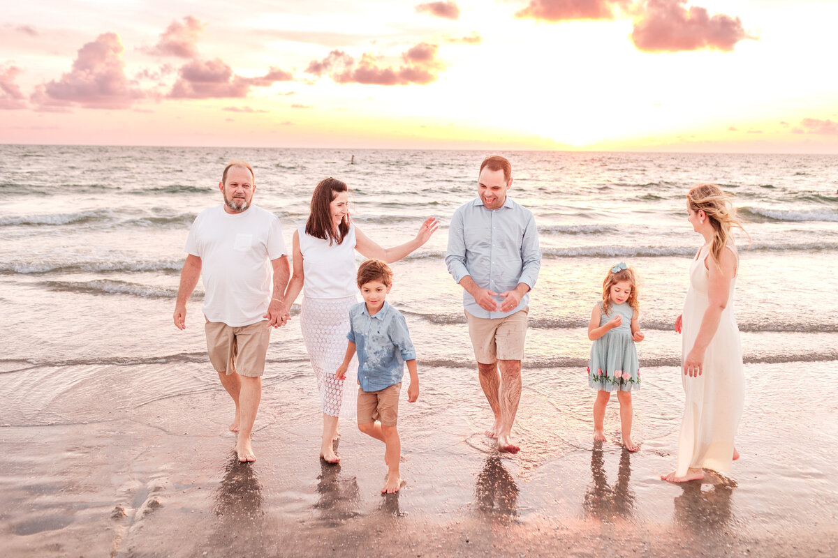 Family vacation photos at Clearwater Beach with calm turquoise waters behind them.