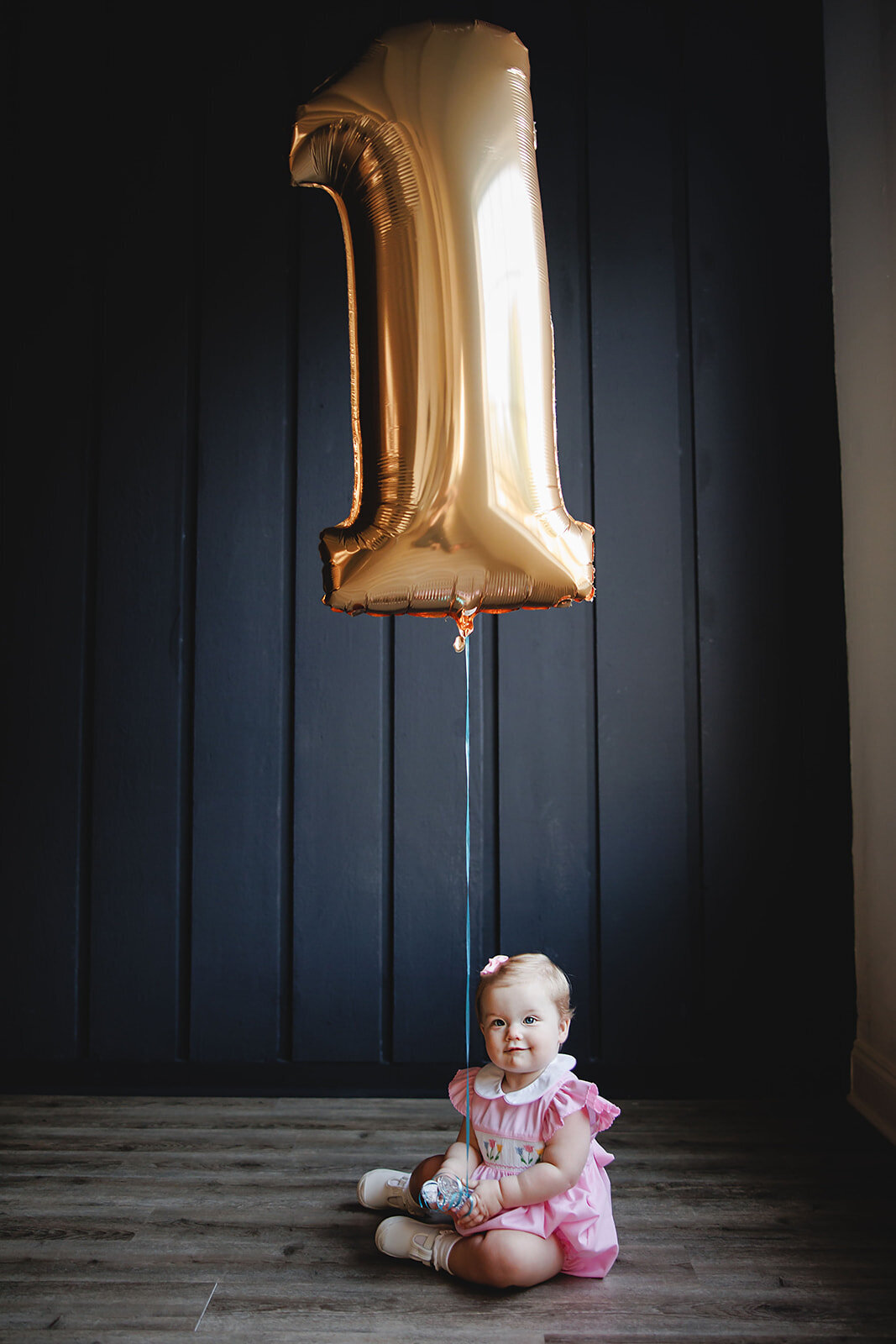 Portrait of a little girl holding a balloon in the shape of a 1