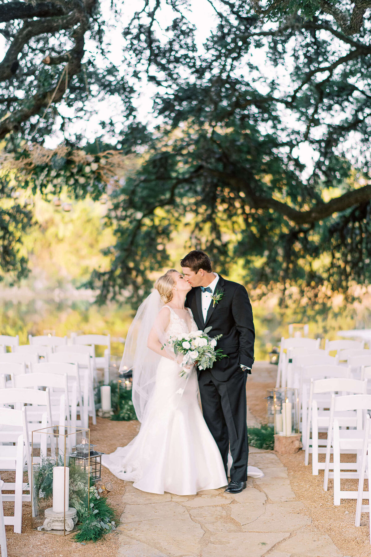 Bride and groom kiss in the aisle underneath oak trees at Tapatio Springs Hill Country Resort
