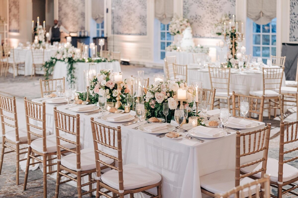 Elegant wedding reception setup with floral centerpieces and gold chairs.