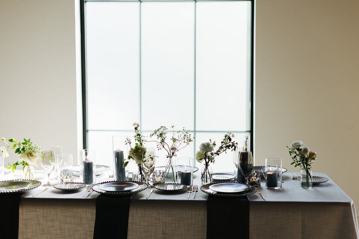 Elegant bud vases with florals of roses, ranunculus, sweet peas, Queen Anne’s lace, butterfly ranunculus in hues of white, cream and blush. Accented with dusty blue tapers and clear glass votives. Designed by Rosemary and Finch in Nashville, TN.