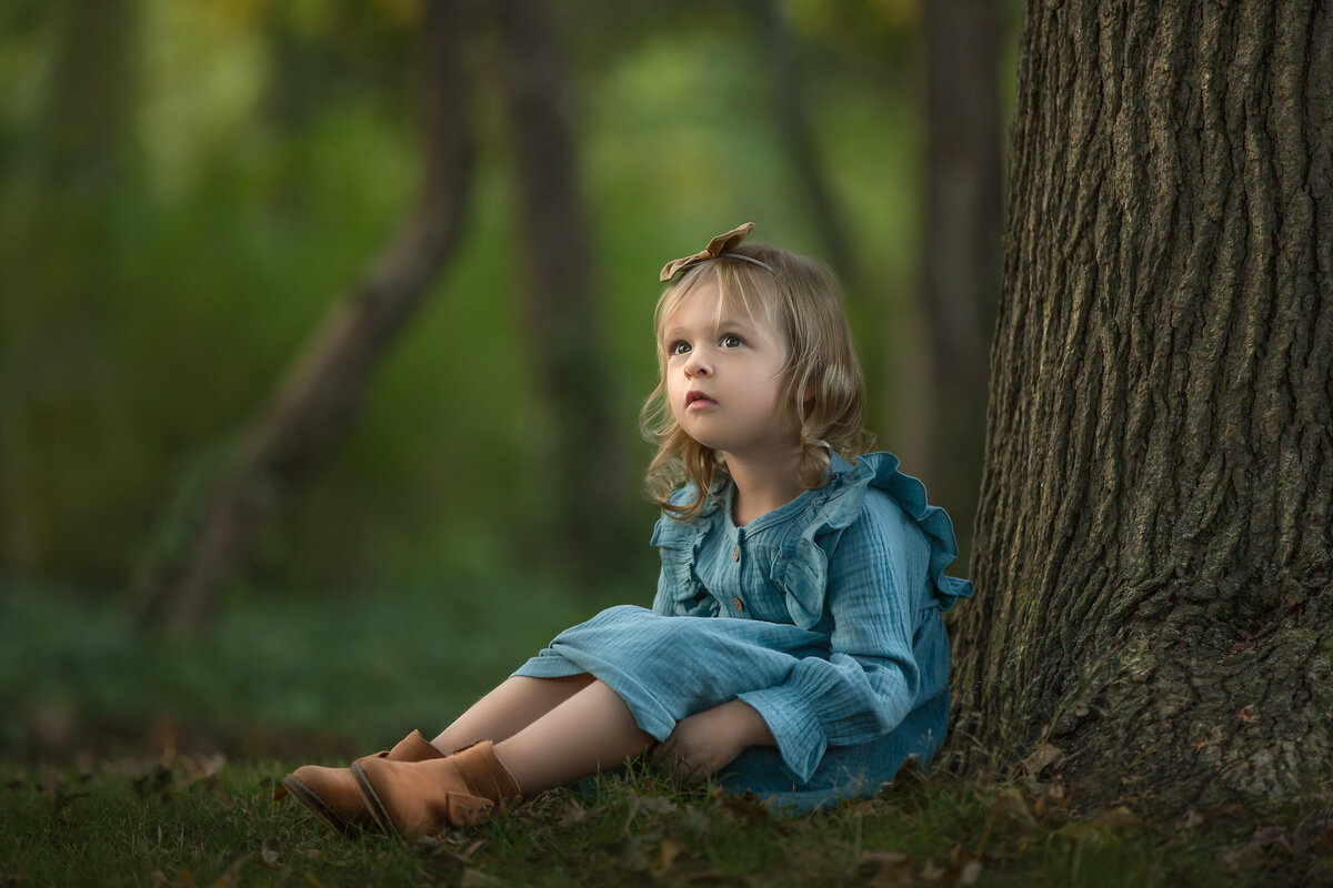 Child leans agains tree for artistic portrait during family photography session in Mount Holly, New Jersey.