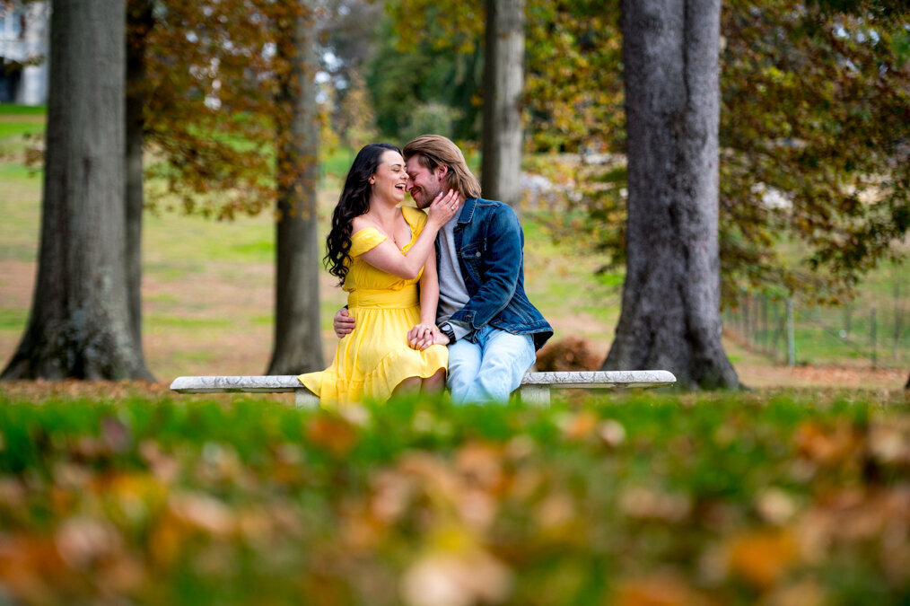 A couple kissing on a bench in a park.