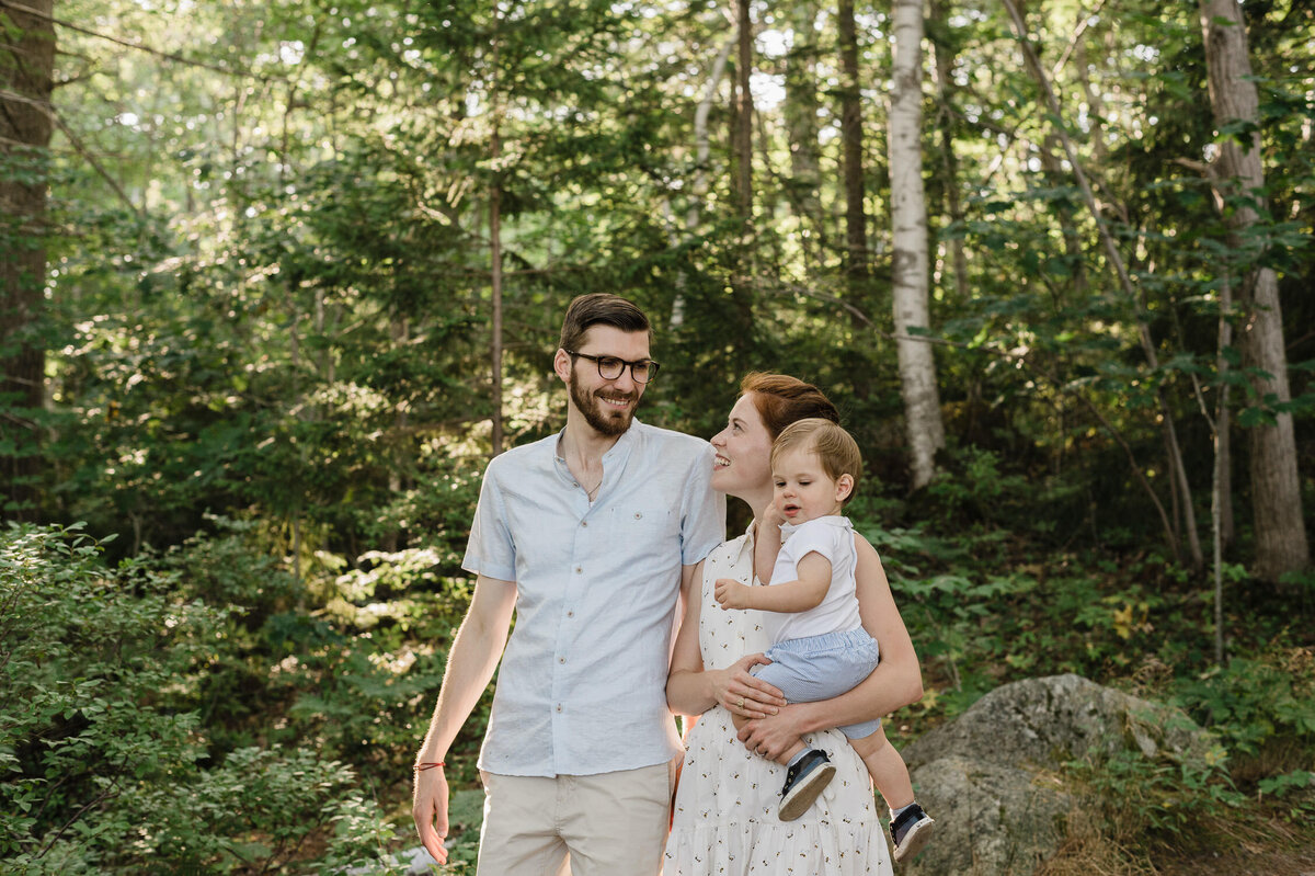 Couple with toddler in the forest on sunny day.