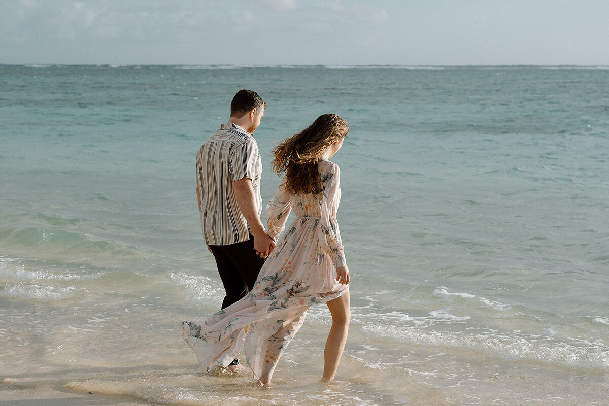 engaged couple walks in the ocean in Hawaii