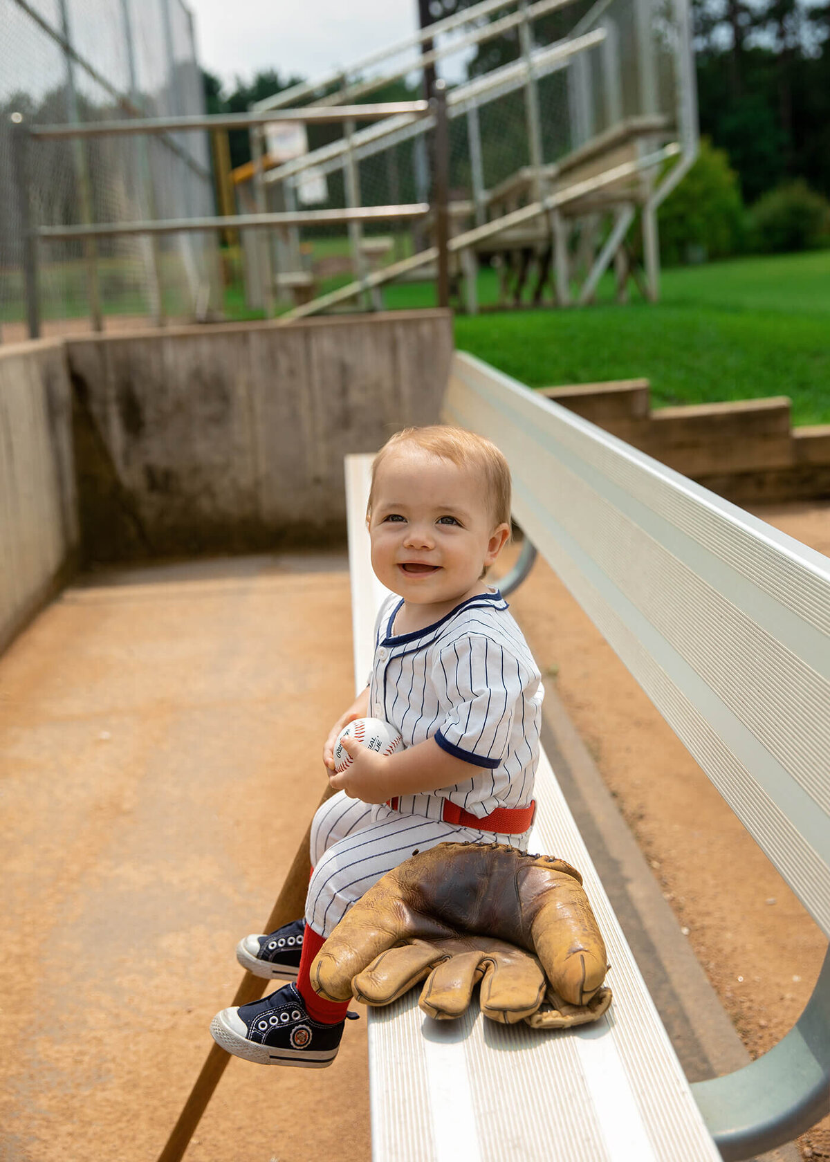 1 year old boy sitting on the dug out bench.