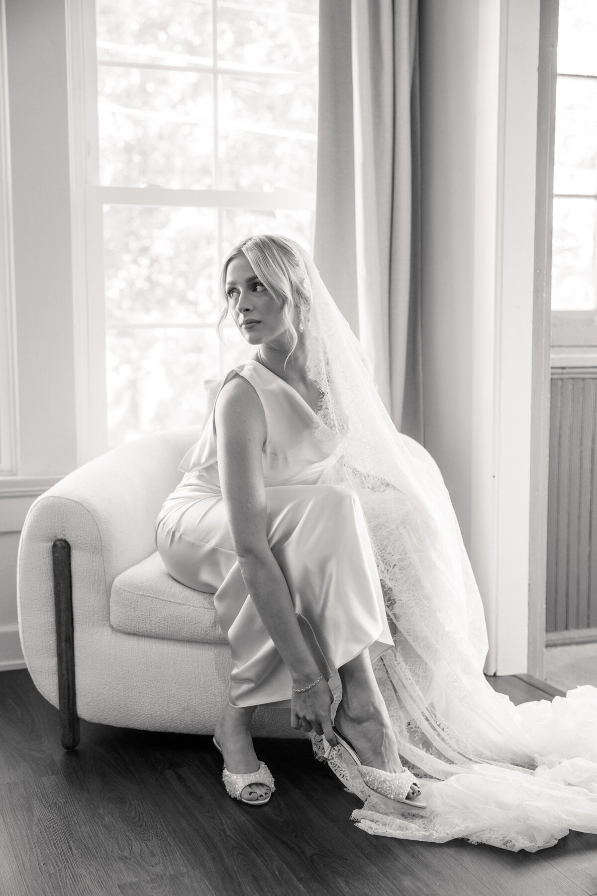 Bride puts on embellished heels in Dayton, Ohio wedding suite, photographed by Philadelphia wedding photographer.