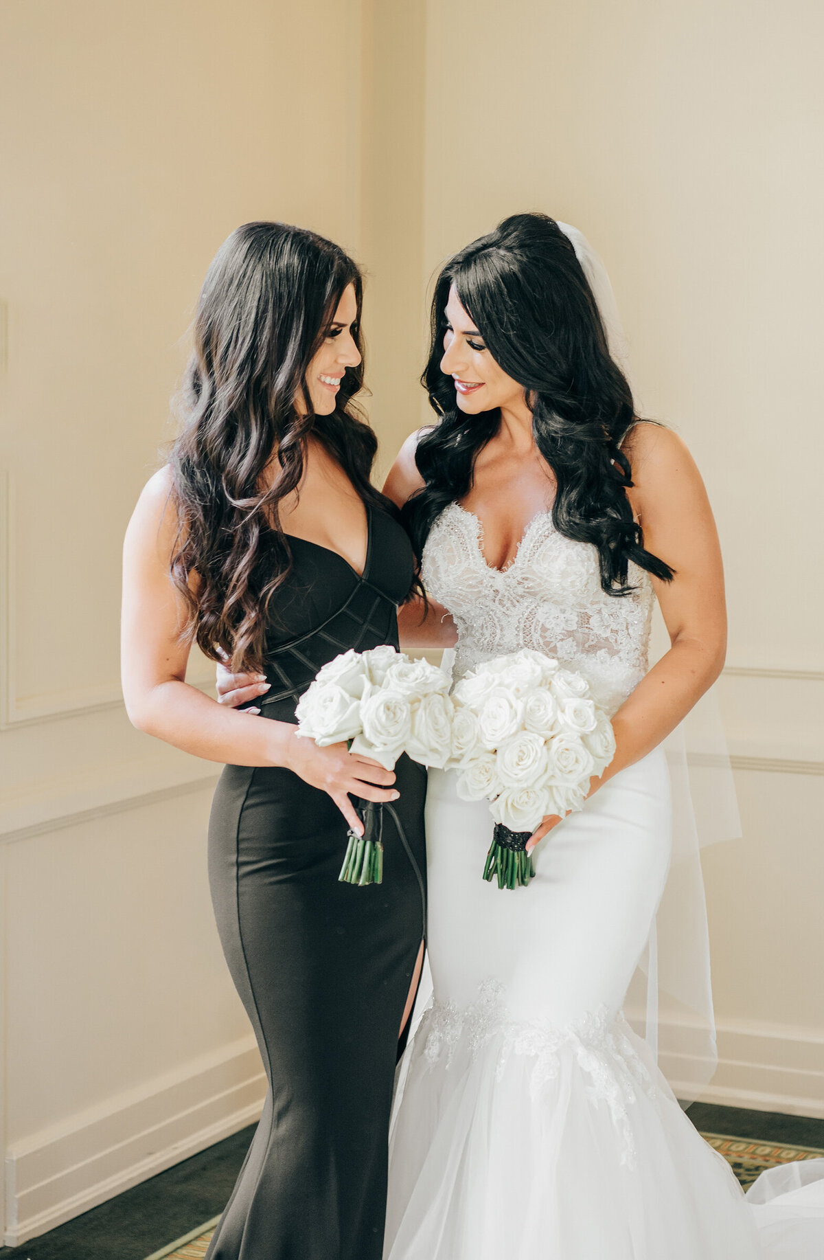 A bride and her maid of honour posing for photos before the wedding ceremony