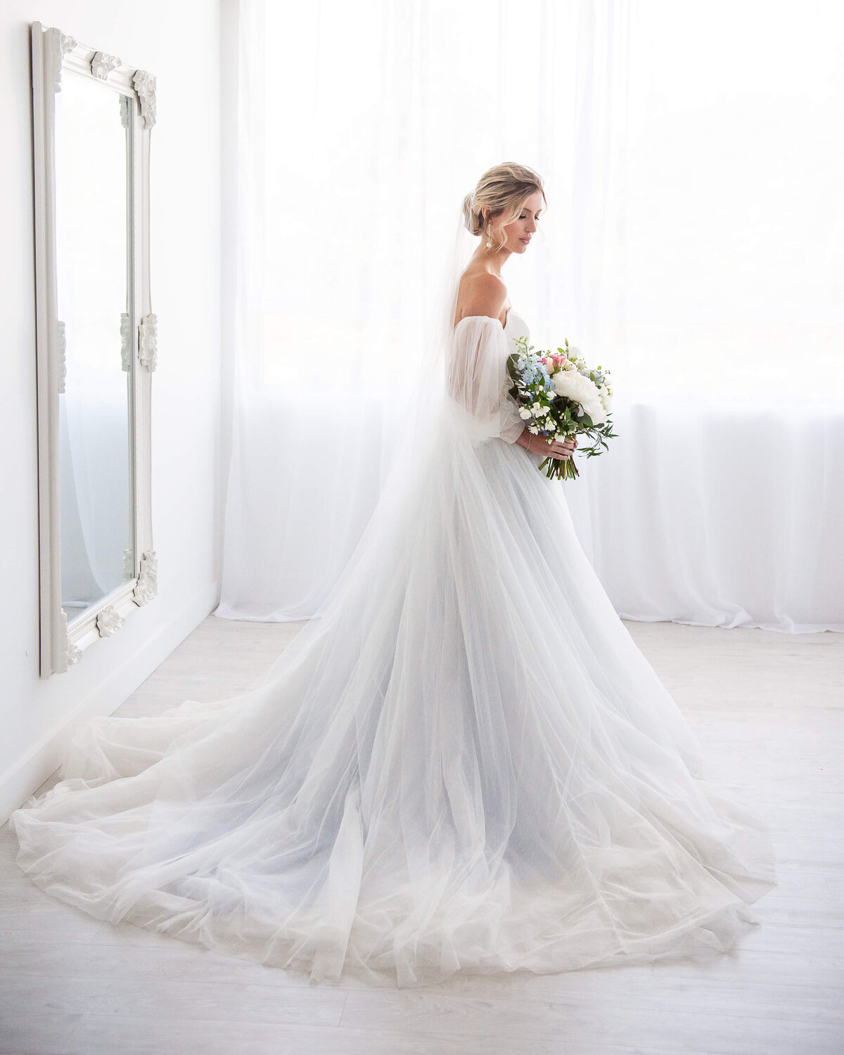 a full length romantic photo of a bride with a wedding gown that has a baby blue underlay.   Captured by Ottawa wedding photographer JEMMAN Photography