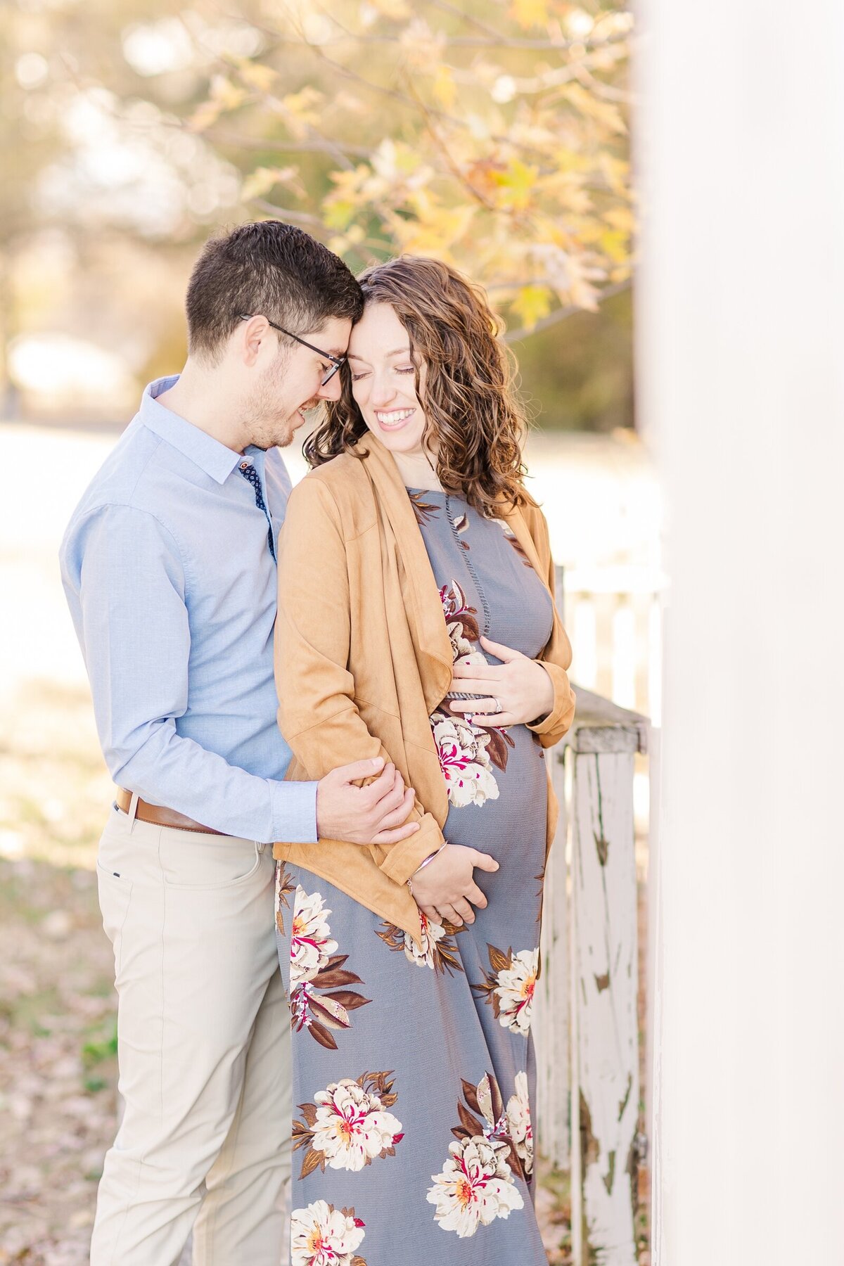 Husband and wife standing forehead to forehead with hands on baby bump