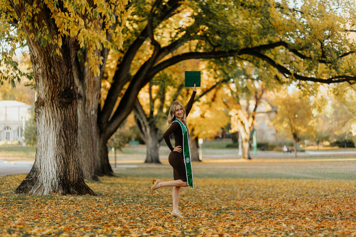A Colorado State University graduate celebrates her achievement by raising her cap in the air during her fall grad session in Fort Collins, Colorado.