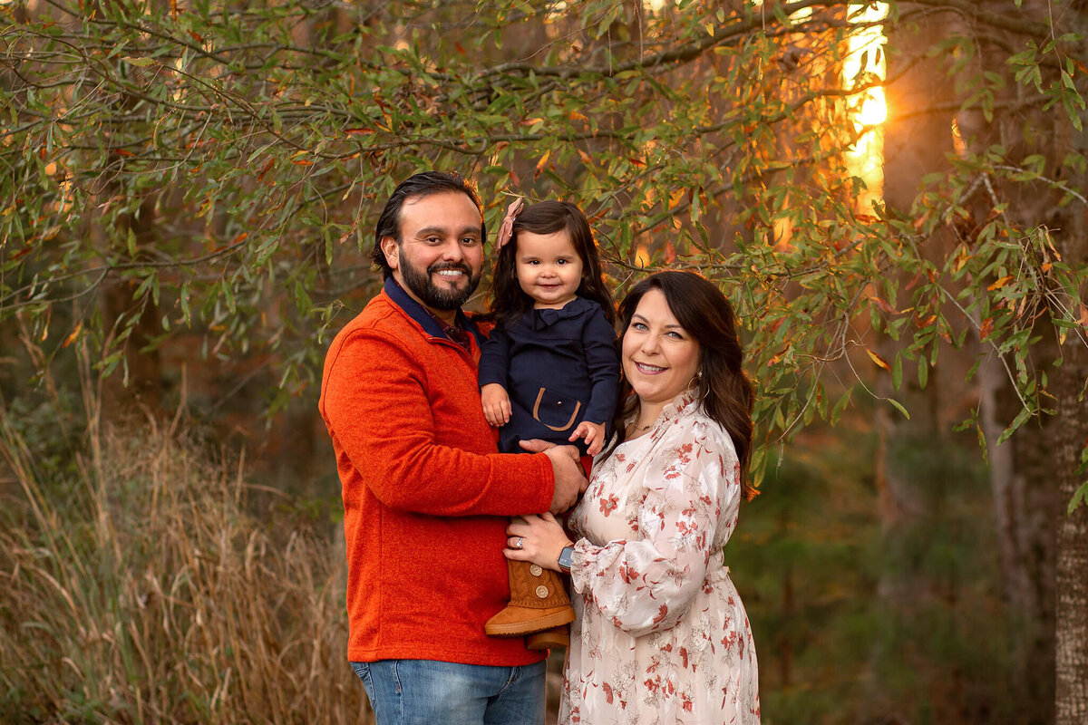 Parents with baby girl at sunset at Forest Ridge Park by Susan VanNess Photography, a Raleigh family photographer.