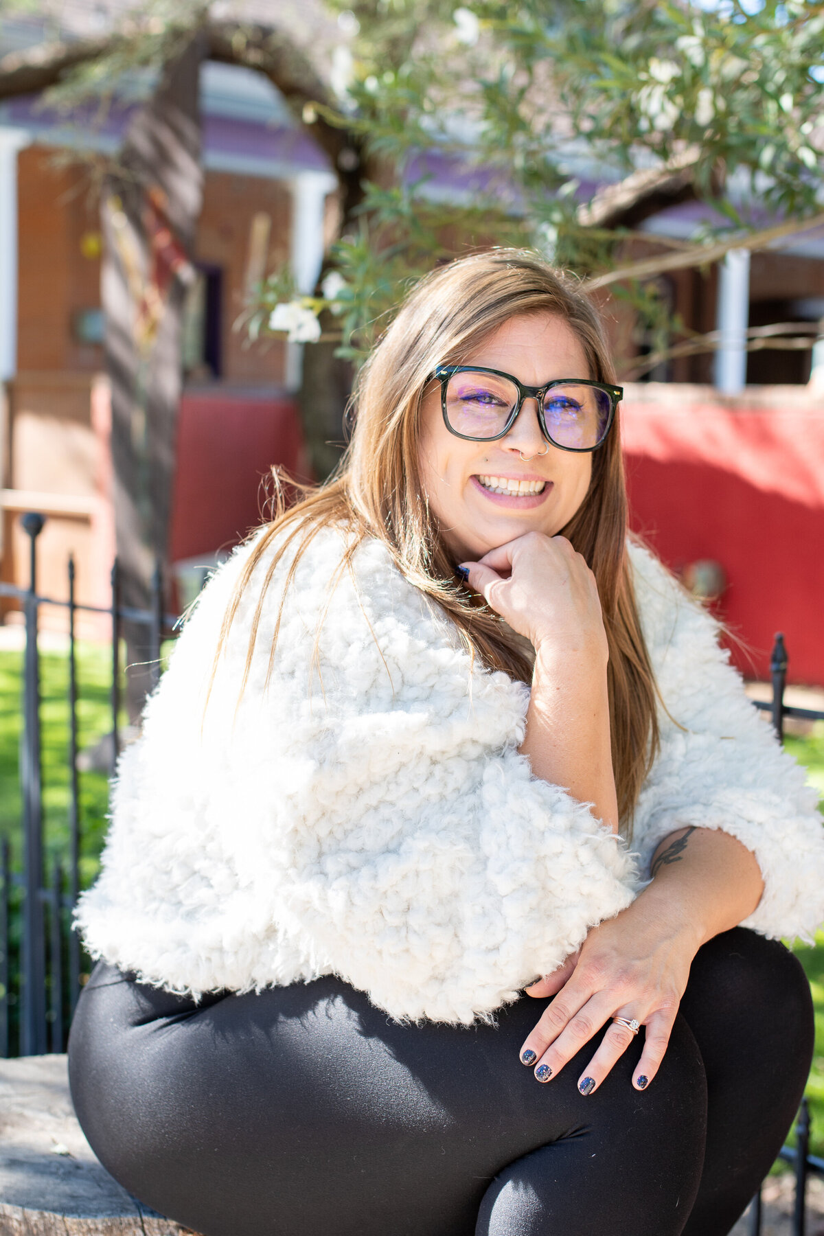 Woman smiling while sitting outdoors in a cozy white jacket and glasses, photographed by Vyrl Photo, showcasing Tucson brand photography.