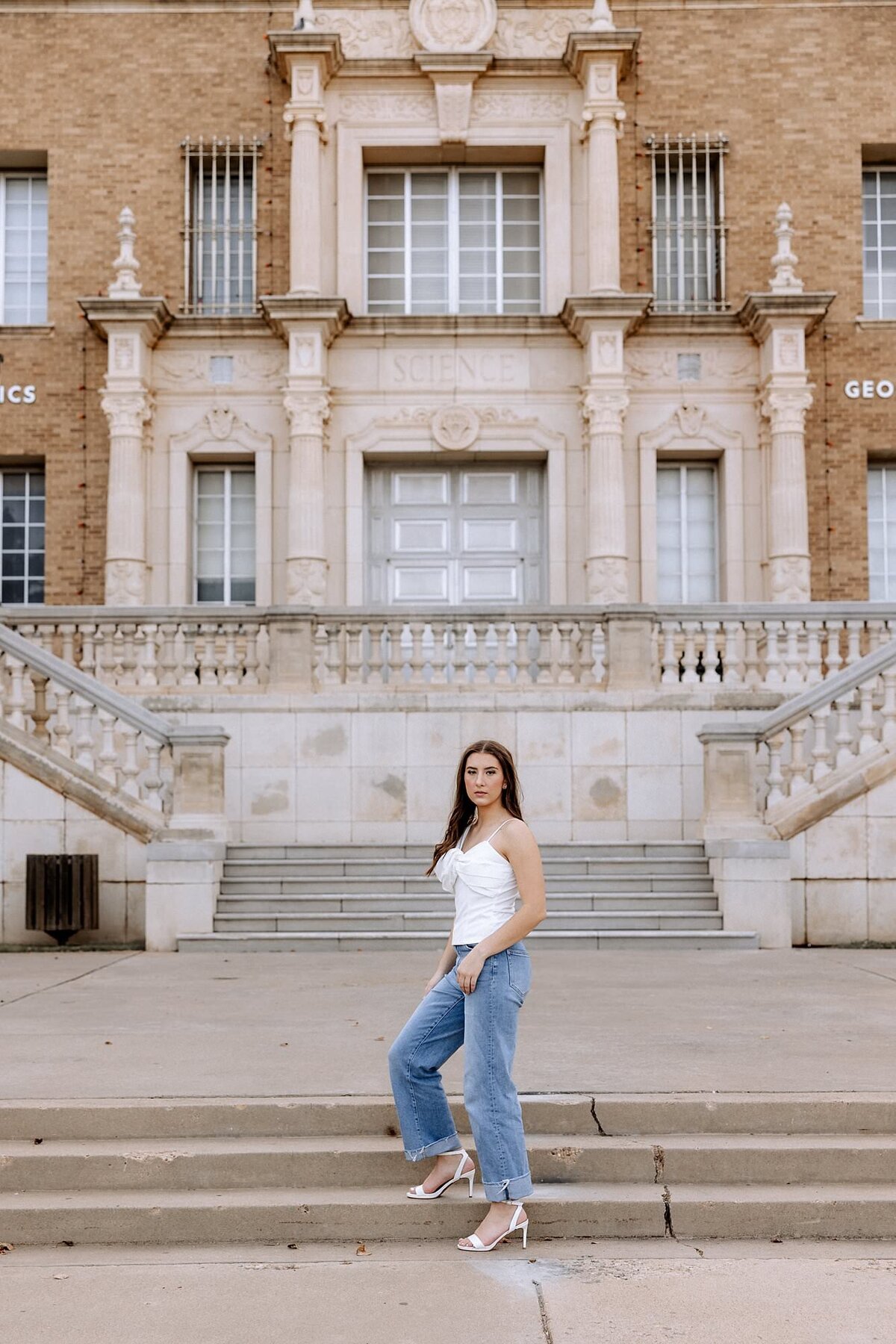 White washed denim jeans with a spaghetti strap white top, this senior poses for the camera.