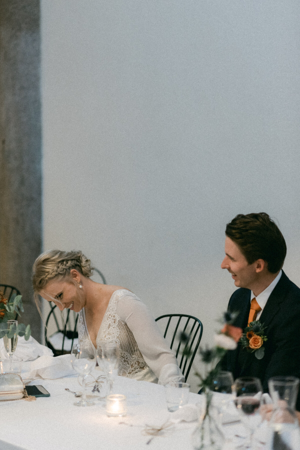 A documentary wedding  photo of the bride and groom laughing at a speech in Oitbacka gård captured by wedding photographer Hannika Gabrielsson in Finland