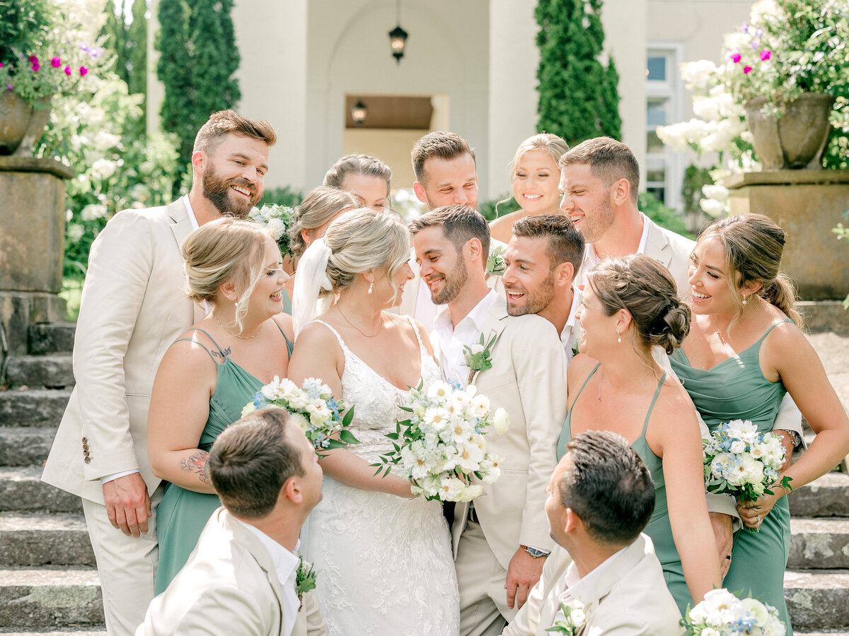 Bride and groom with their heads together surrounded by their smiling wedding party