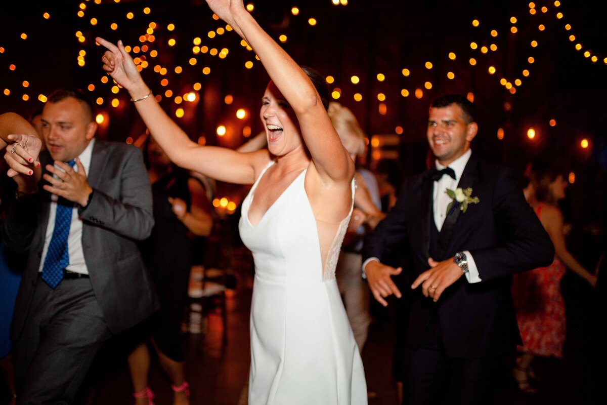 Bride cheers as she greets guests during her reception at Saltwater Farms Vineyard.