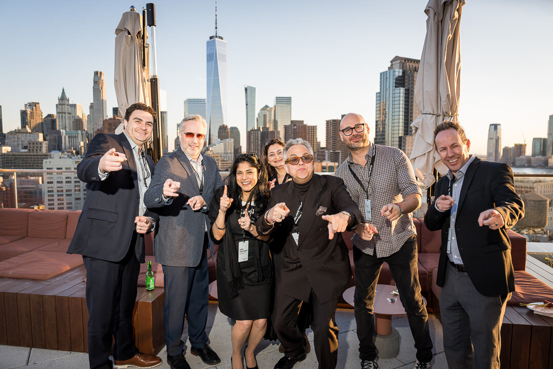 Corporate event photo of professionals networking outdoors with new york city skyline background.