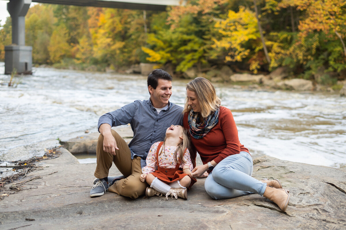 family smiling sitting by a river outdoor fall family session Olmsted Falls