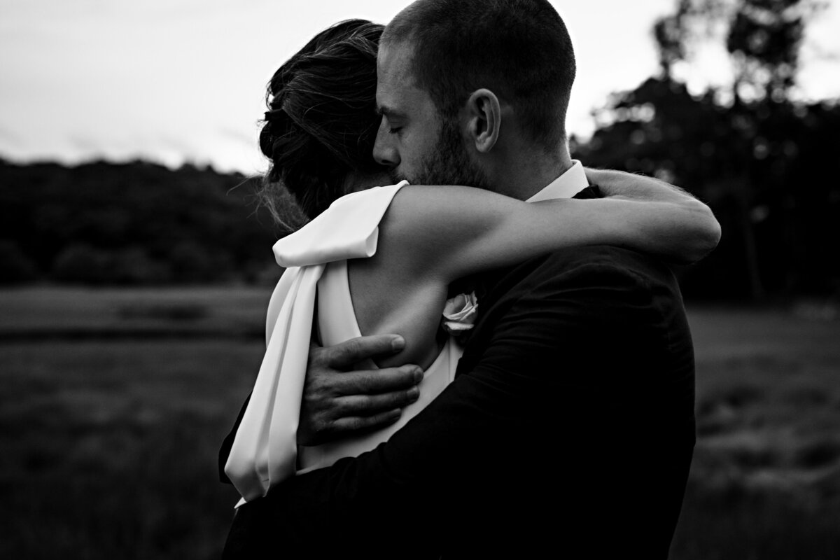 Newlyweds embrace in the tall sea grass at Dockside Guest Quarters in maine