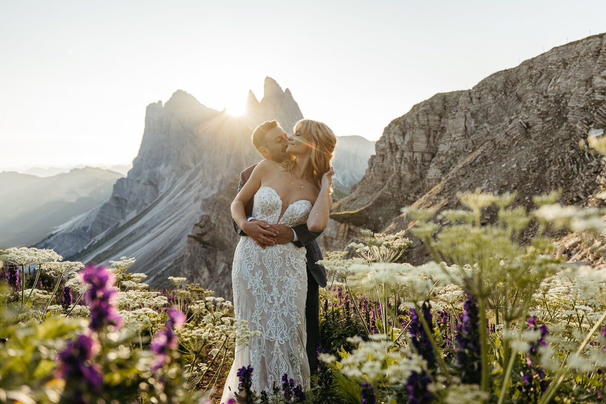 Bride and groom surrounded by purple wildflowers Dolomites