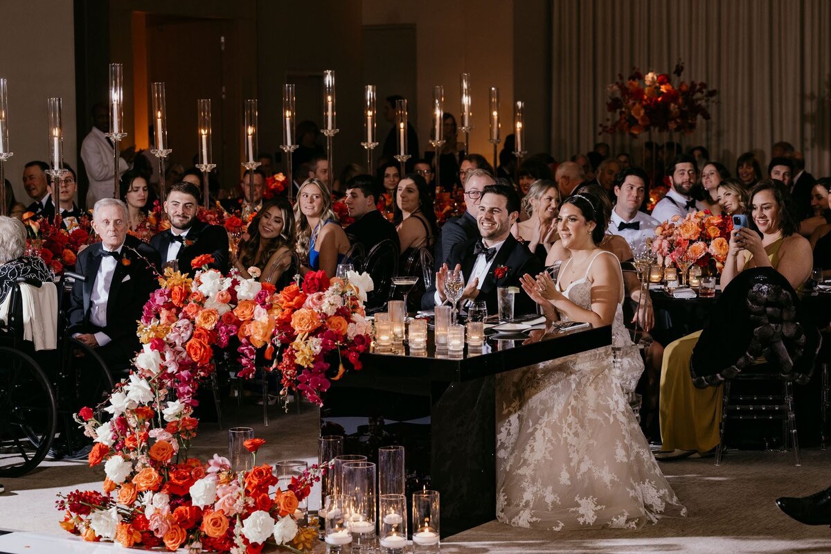 Bride and Groom sitting at modern sweetheart table with asymmetrical florals by Philadelphia wedding florist Sebesta Design