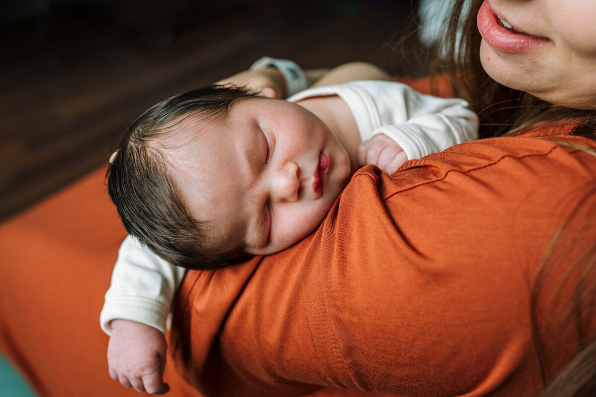 newborn sleeping on mom's shoulder in the hospital