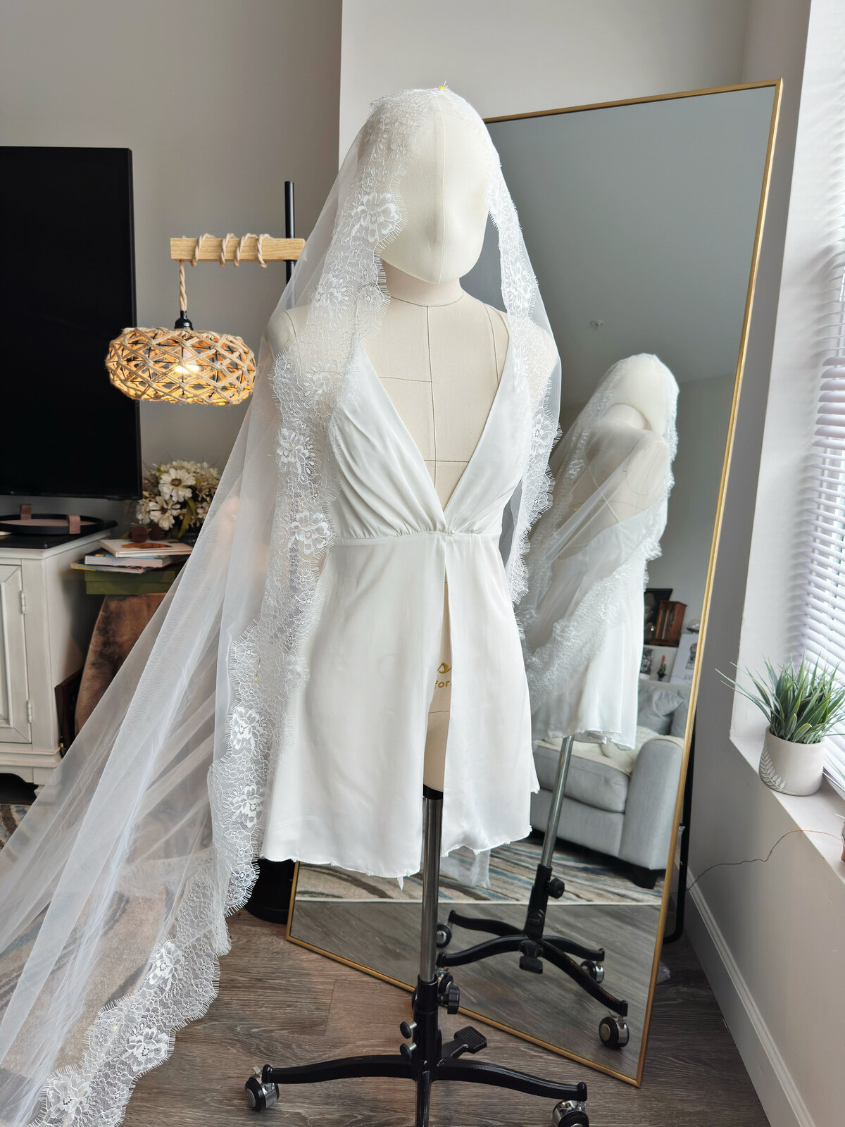 Bride walking outdoors with long lace mantilla veil trailing behind”