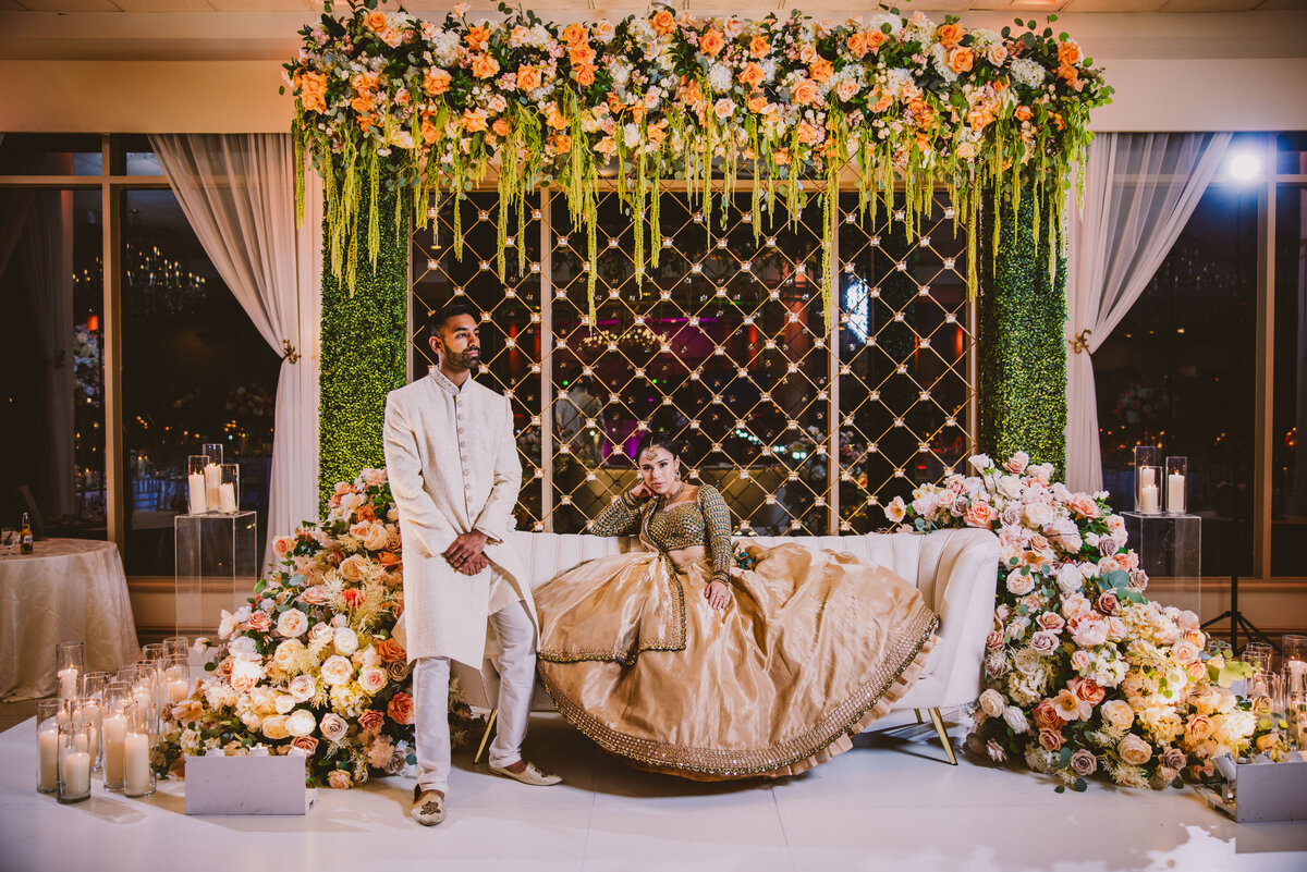 A mixed fusion indian mexican bride and groom sitting on stage at their wedding reception in the greentree country club in new rochelle ny