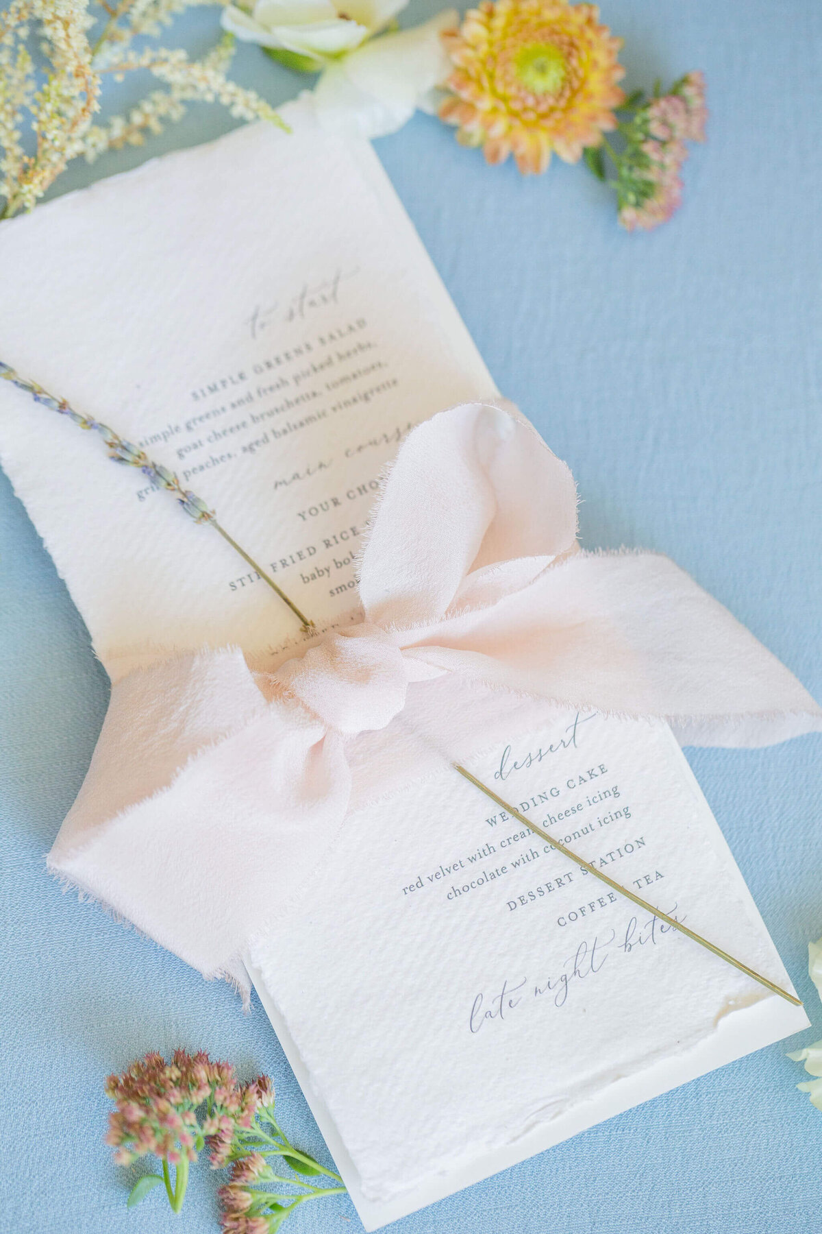 Wedding dinner menu wrapped in a pink ribbon and adorned wtih a sprig of lavendar