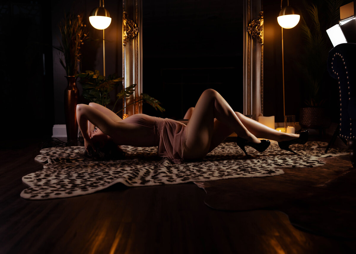 woman laying on ground in lingerie during after dark session in front of mirror with leopard print rug