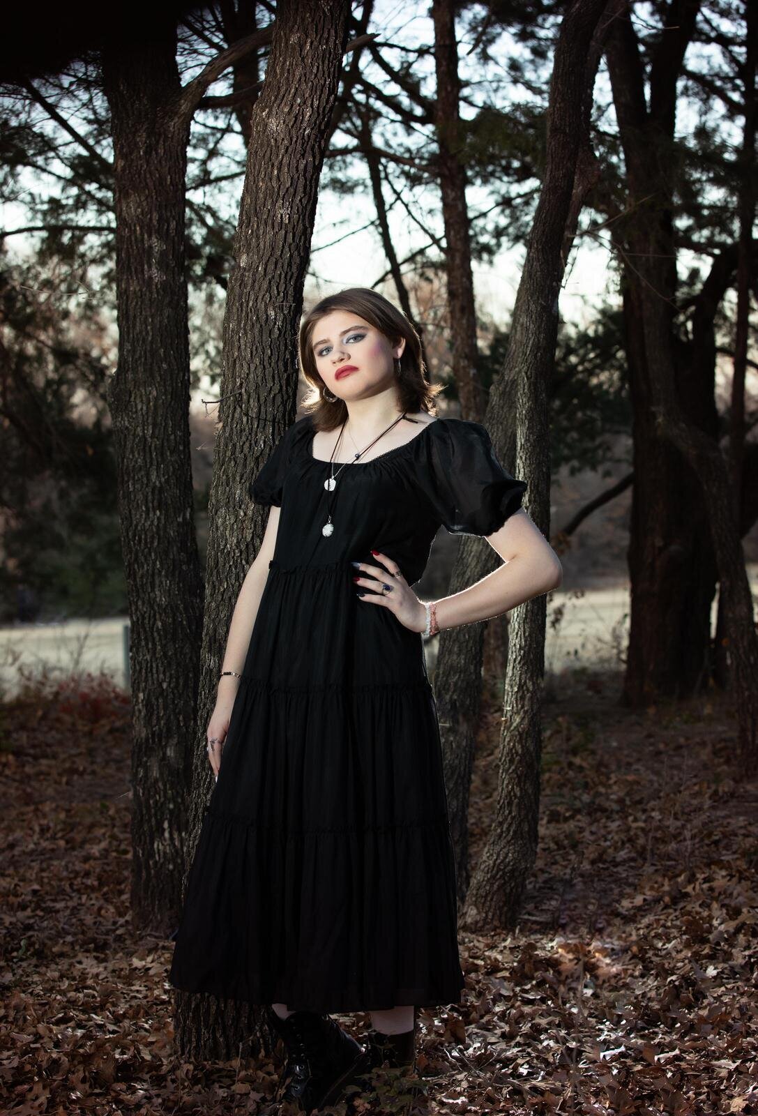 senior-girl-posing-in-black-dress-in-forest