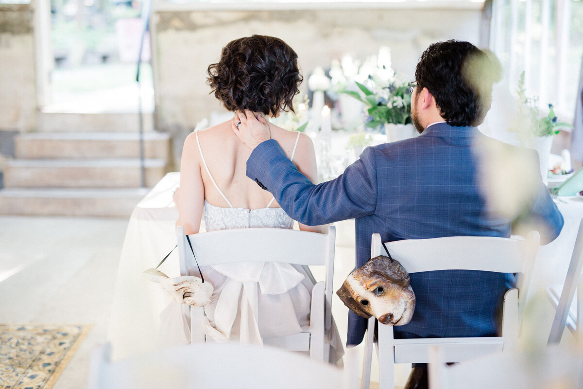 Candid photo of groom with hand in bride's back at Historic Shady Lane greenhouse wedding