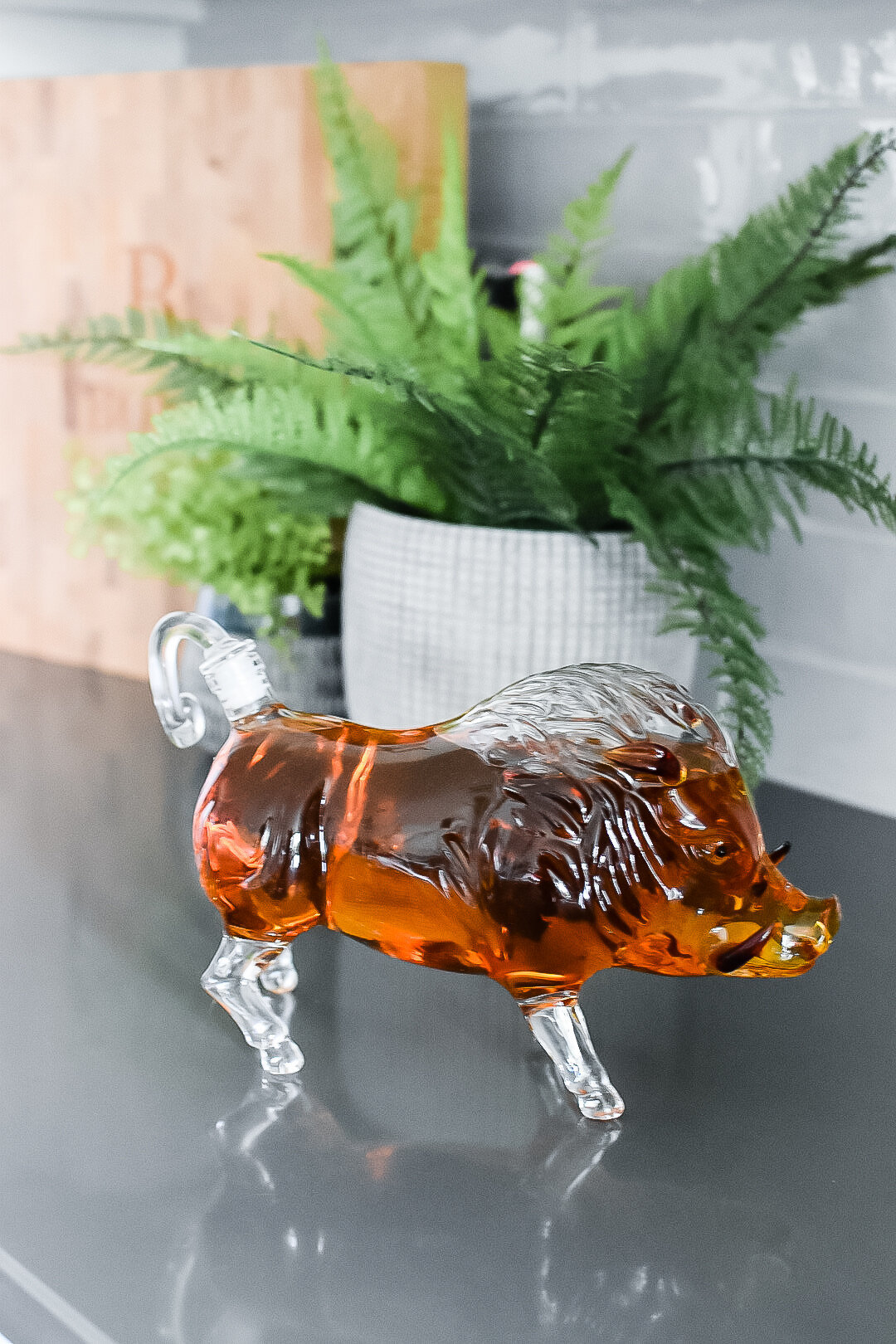 A glass statue sits in front of a potted plant on a kitchen countertop