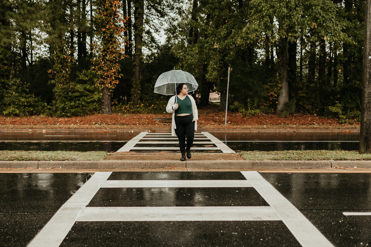 woman under clear umbrella walks on crosswalk