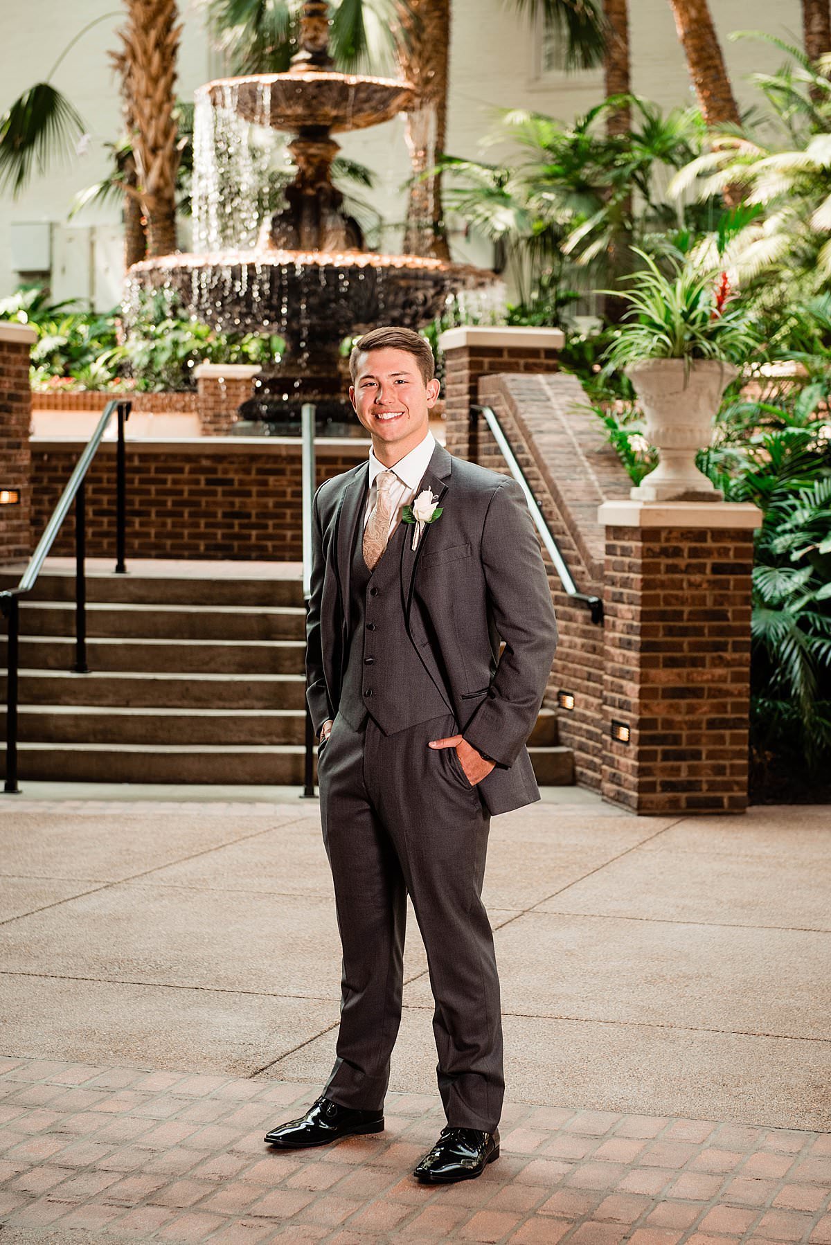 Groom standing in Gaylord Opryland hotel with fountain in the background