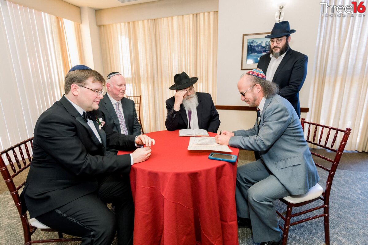 Groom meets with others to sign paperwork in the Jewish faith