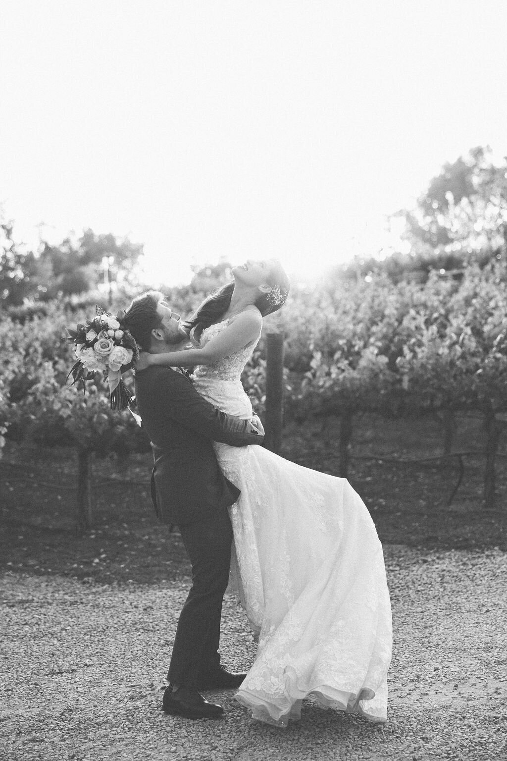Kohnur couple portrait with bride in natural glowing makeup and romantic updo, wearing a sheer gown, posing outside an Italian villa entryway.