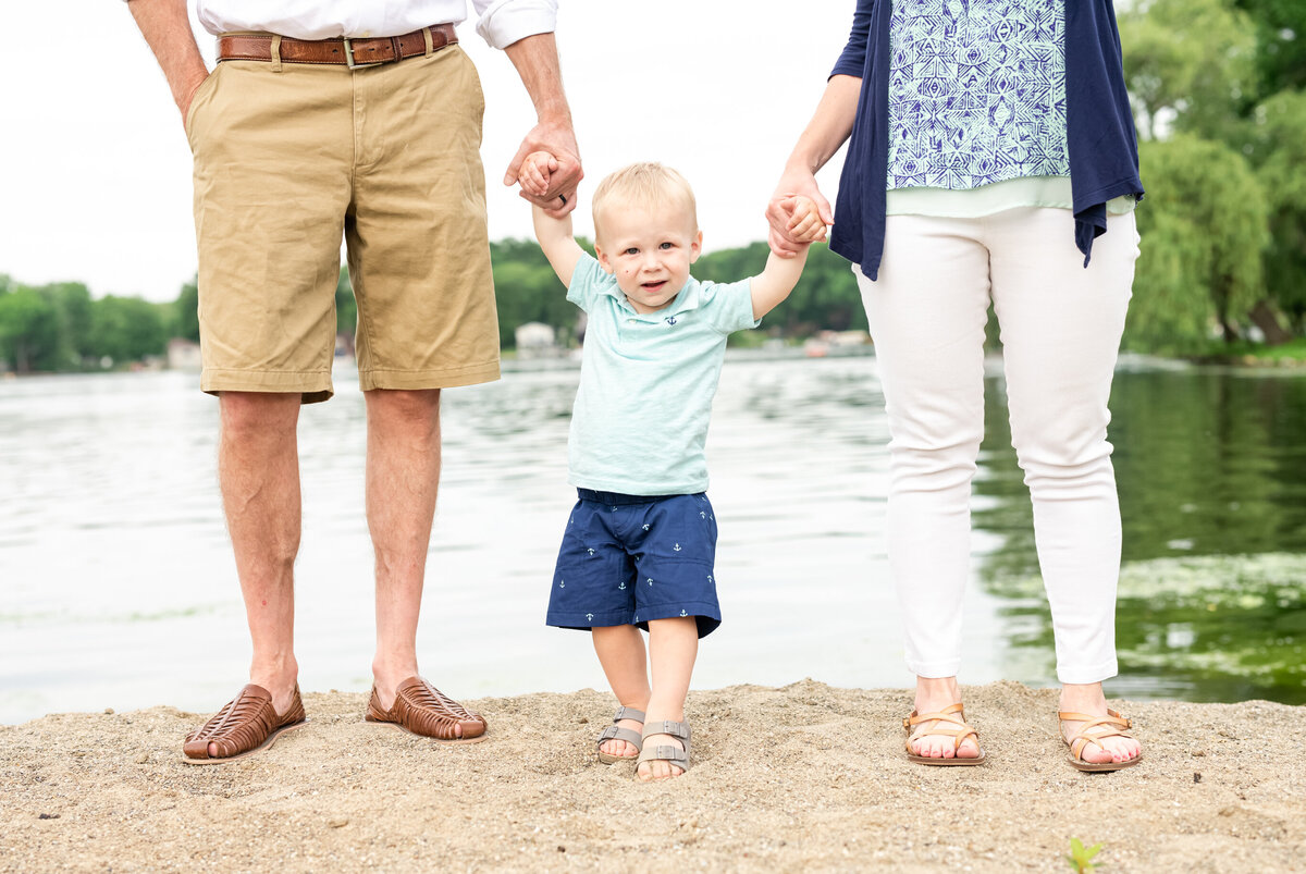 toddler boy holding hands of parents