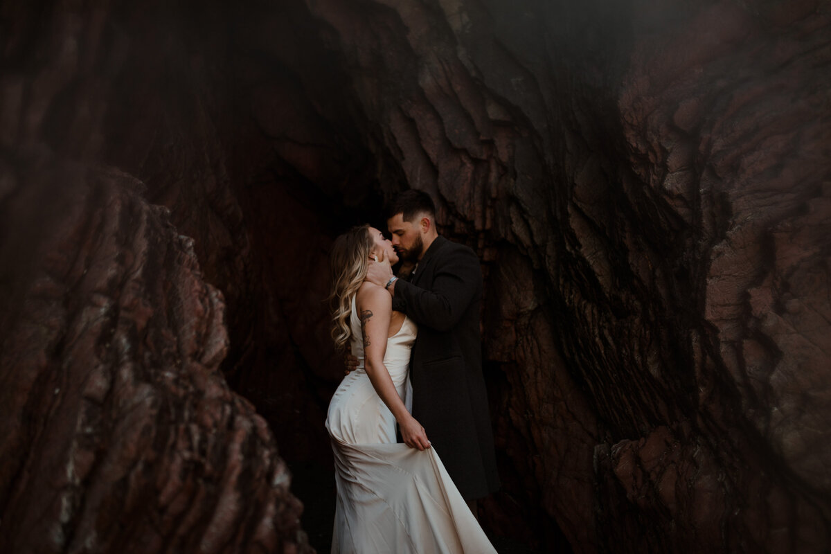 bride and groom kissing by rock