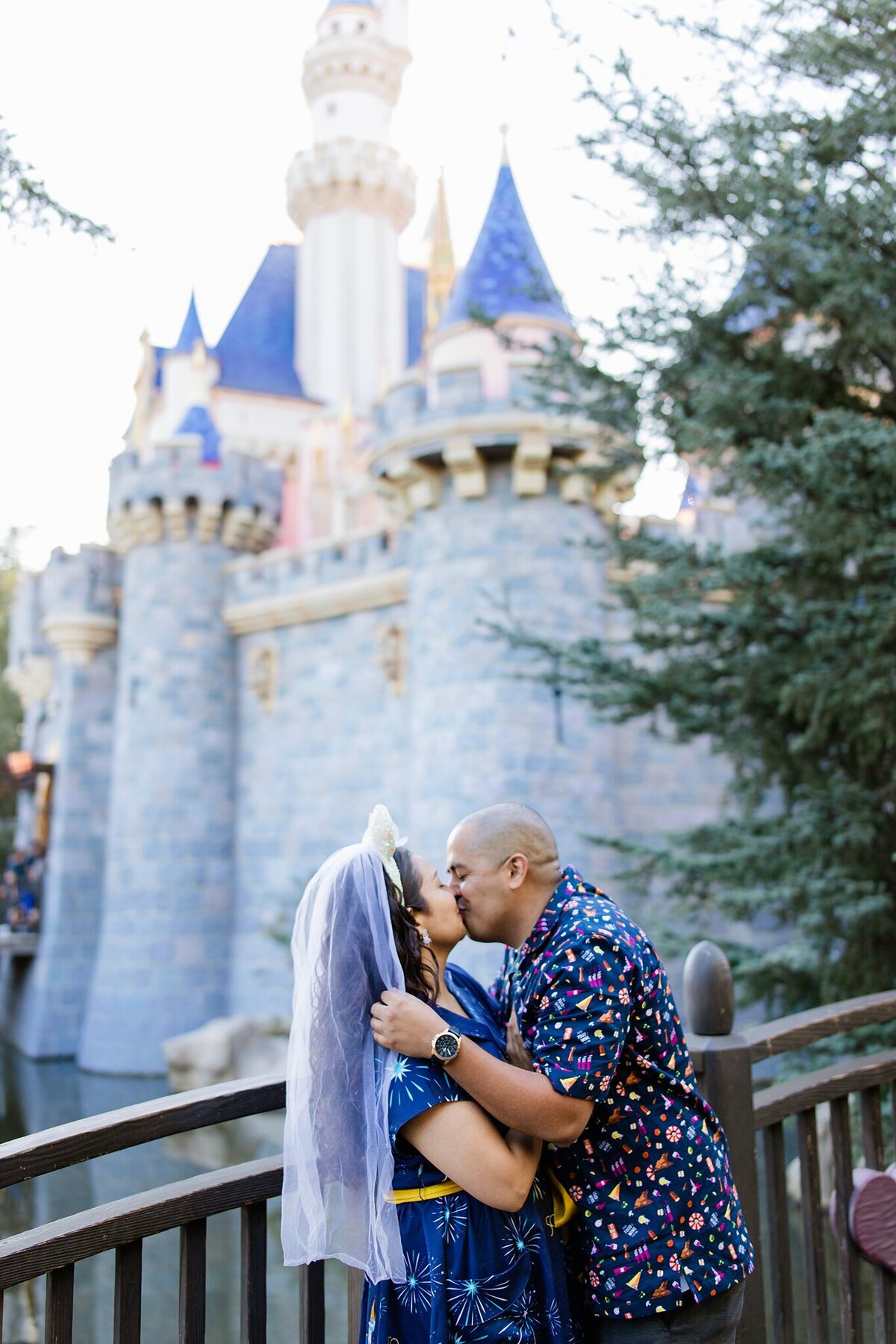 groom kisses bride wearing mickey mouse wedding veil