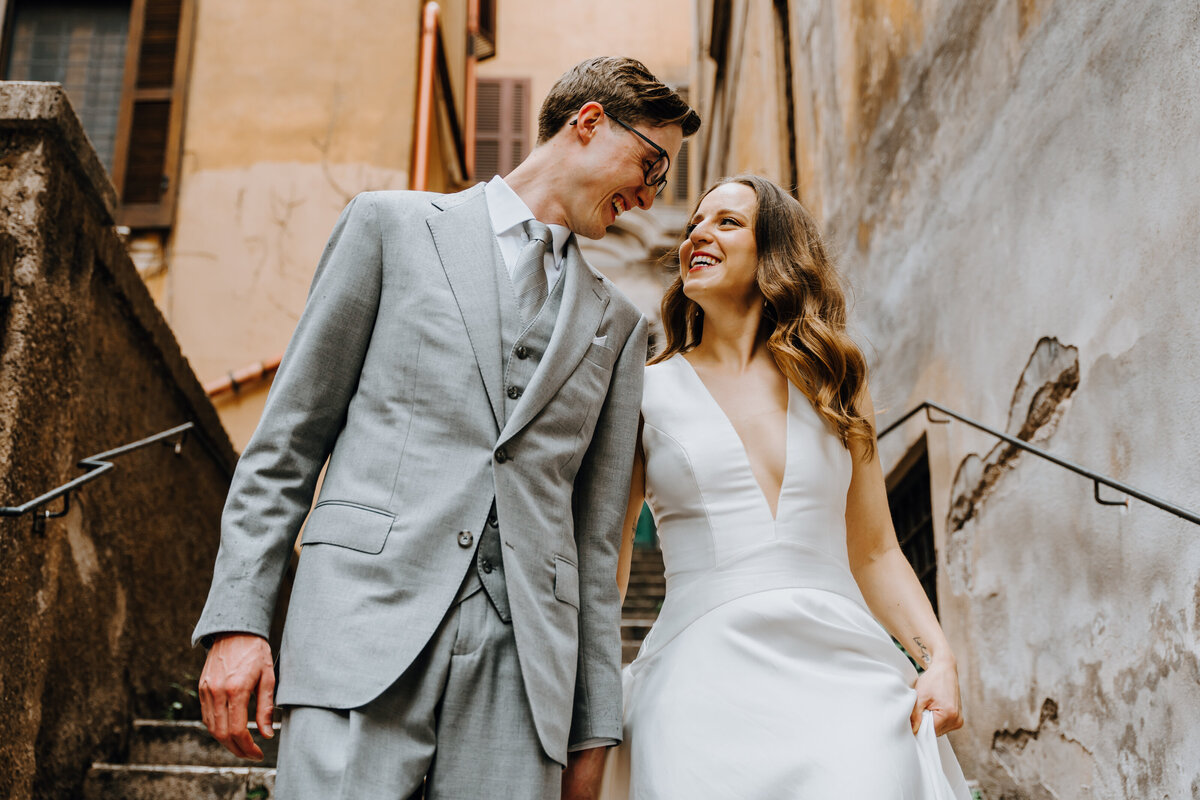 Couple standing on stone staircase in narrow Roman alley.