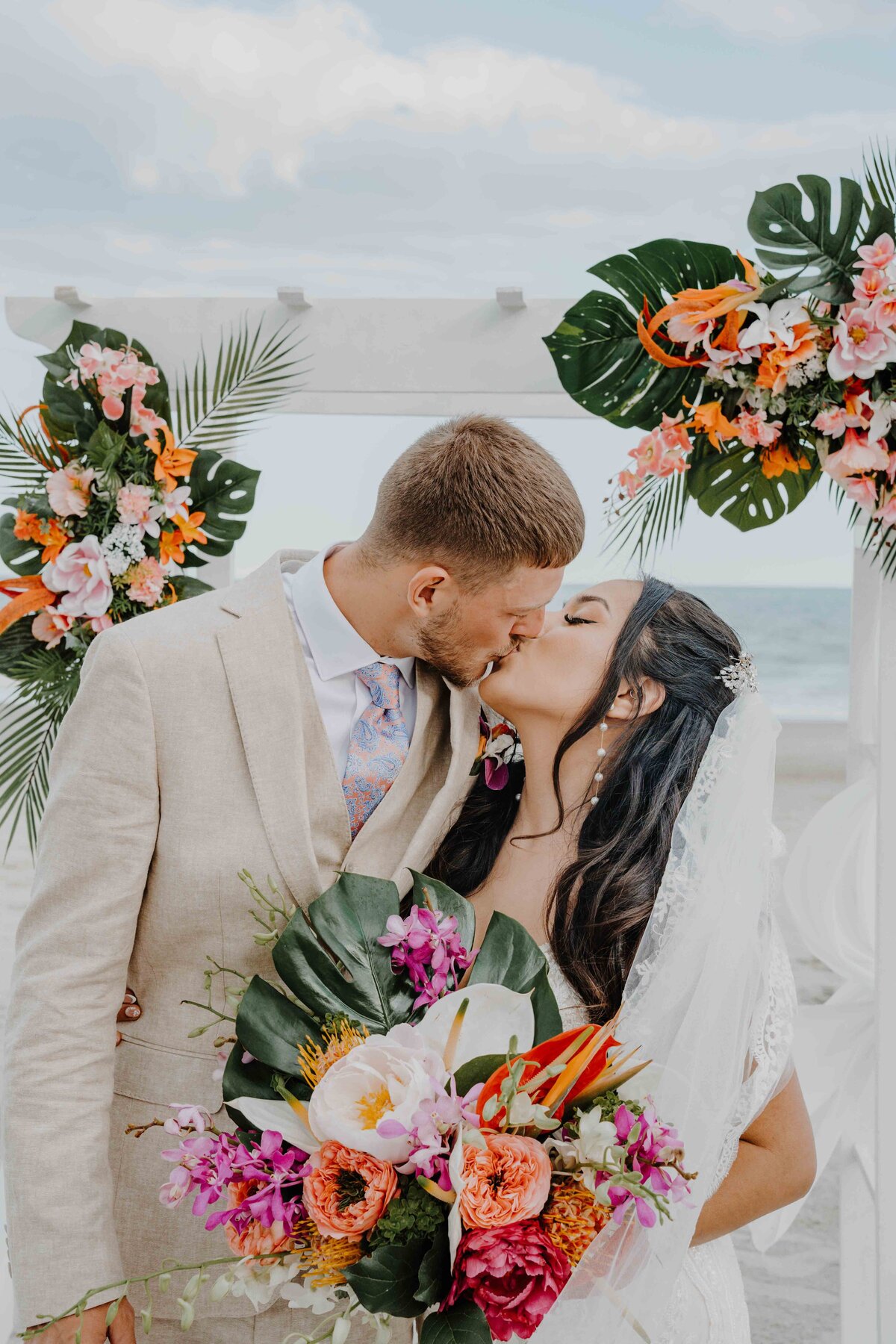 a couple kissing on the beach after ceremony