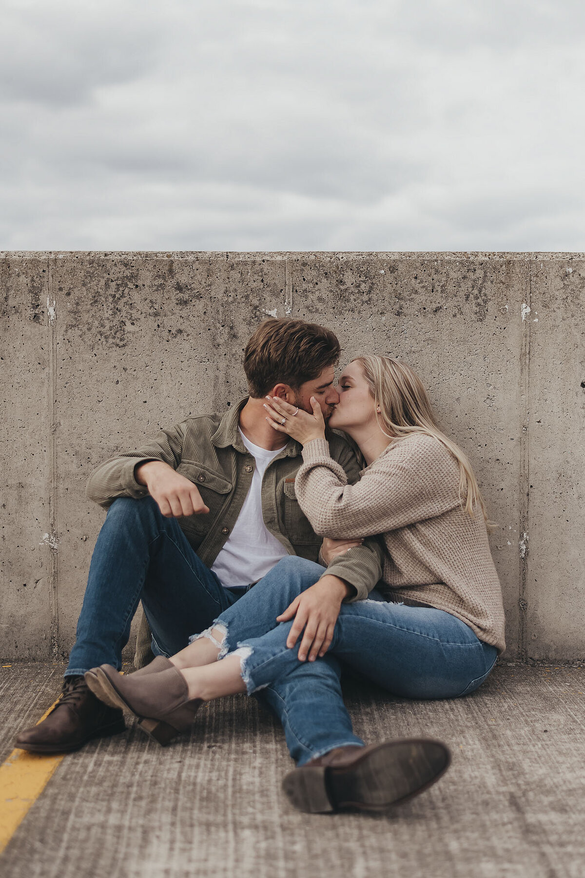 two fiances relaxing together and kissing on concrete