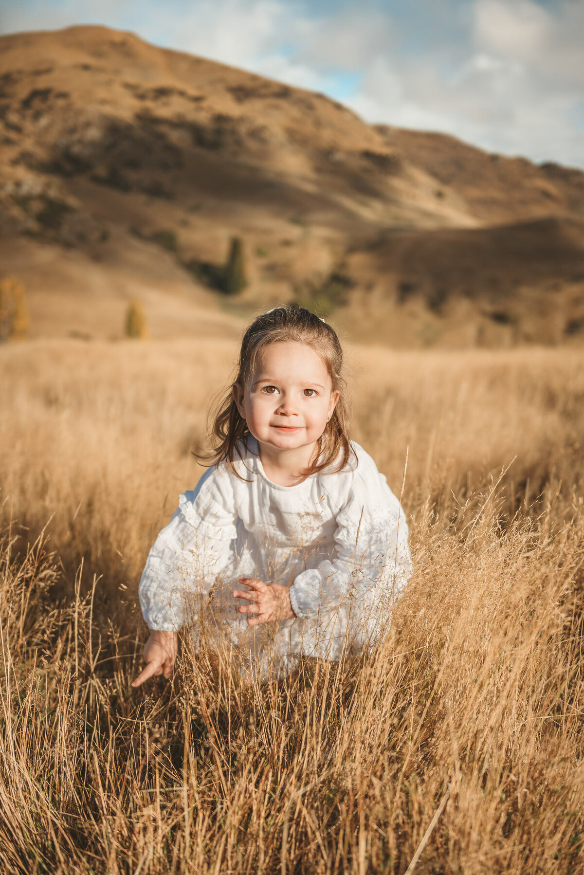 a girl posing in the grass during a Queenstown family photography session captured by Bie